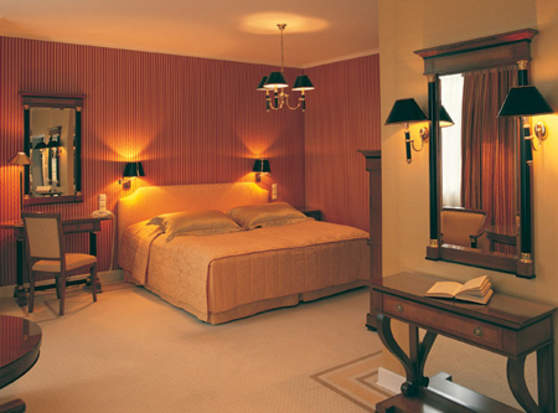 Gemütliches Hotelzimmer mit Doppelbett, Schreibtisch, Spiegel und warmem Licht.