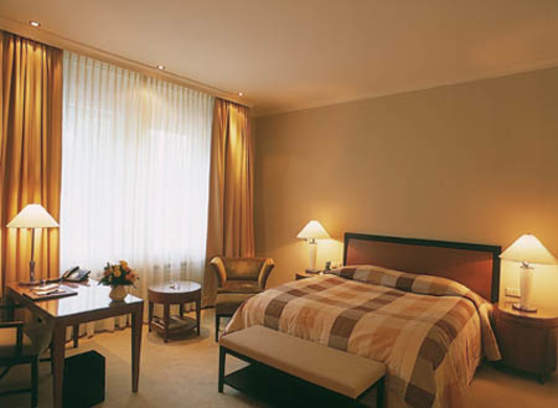 Modernes Hotelzimmer mit Doppelbett, Schreibtisch, Sitzbereich und warmem Licht.