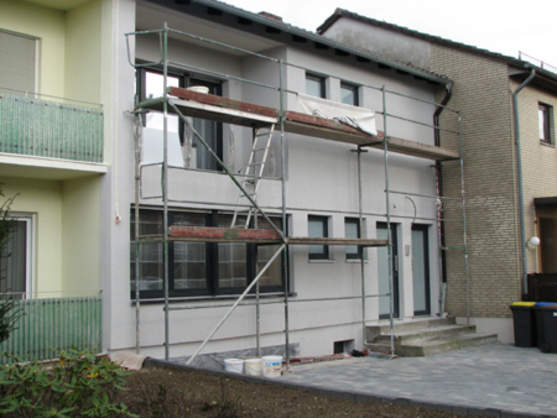 Fassade eines Einfamilienhauses mit Baugerüst für Sanierung oder Fassadenrenovierung.